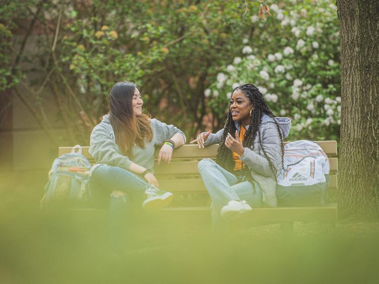 Two people talking on a bench